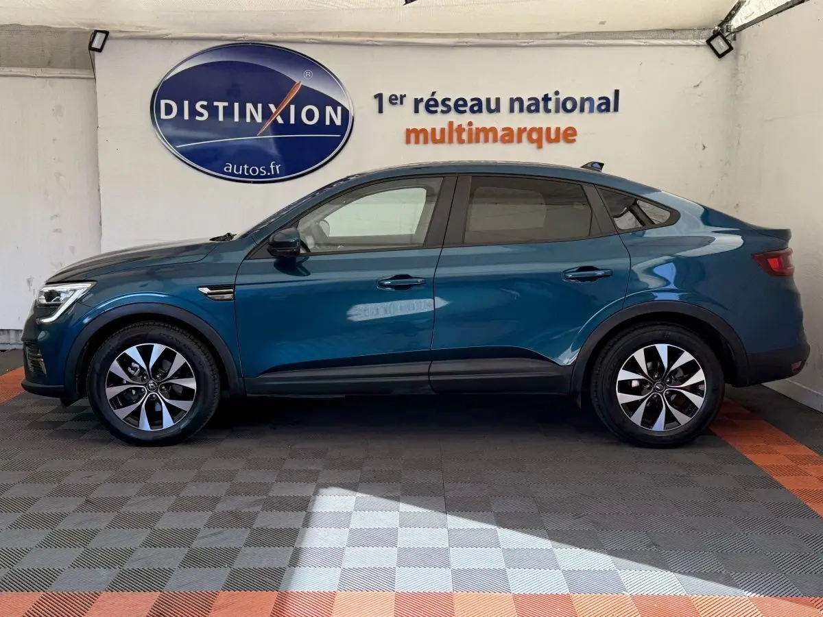 Profil côté gauche d'un Renault Arkana Business E-TECH 145 bleu, avec jantes alliage et ligne de toit plongeante.