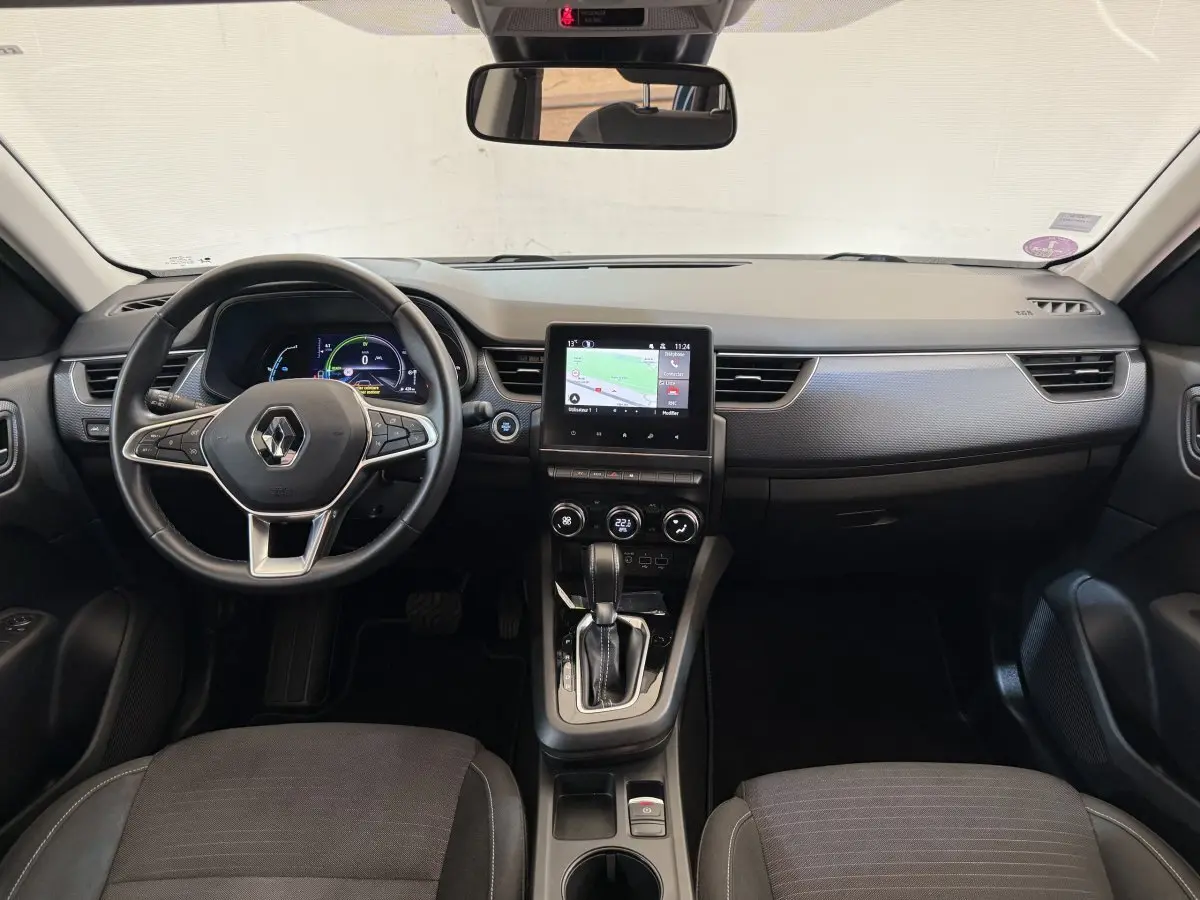 Vue intérieure frontale du tableau de bord du Renault Arkana Business E-TECH 145 avec écran tactile et volant multifonctions cuir.