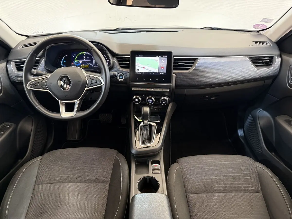 Vue intérieure avant du Renault Arkana Business E-TECH 145 2022, tableau de bord noir avec écran tactile central et volant multifonctions.