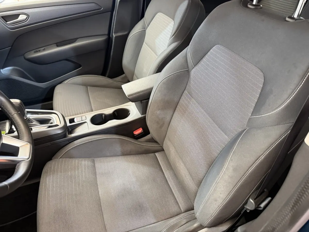 Vue intérieure côté conducteur du Renault Arkana Business E-TECH 145, sièges gris avec accoudoir central et console.