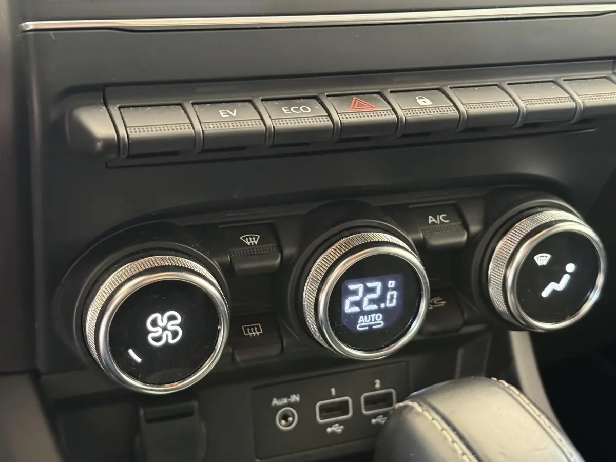 Gros plan sur les commandes de climatisation digitale et boutons de fonction du tableau de bord du Renault Arkana Business E-TECH 145.