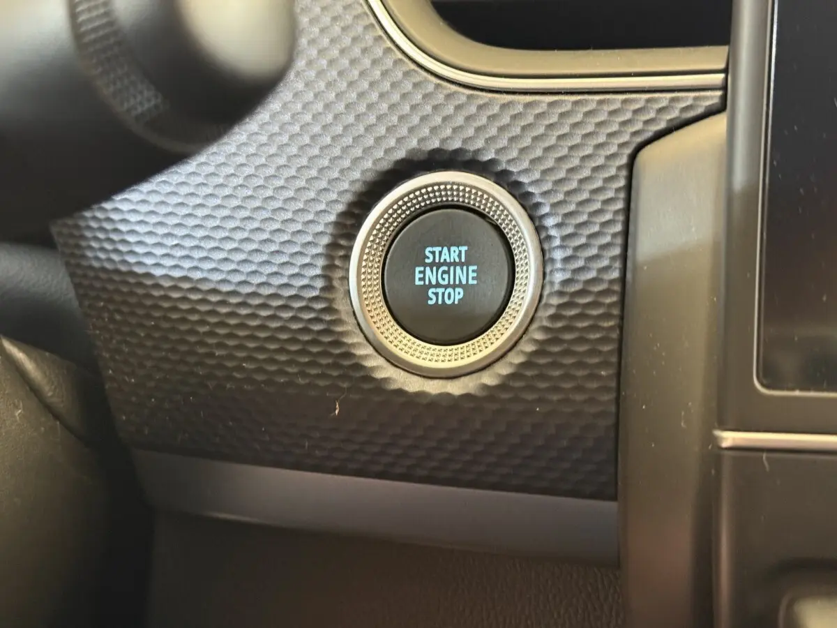 Gros plan sur le bouton start engine stop entouré d’un décor texturé noir dans l’habitacle du Renault Arkana Business E-TECH 145.