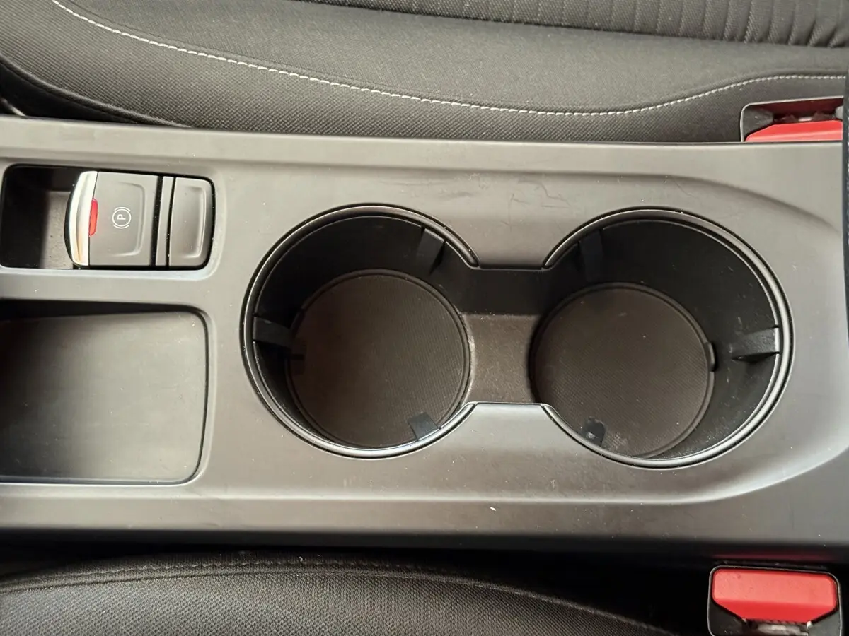 Gros plan sur la console centrale noire avec porte-gobelets et frein à main électrique de la Renault Arkana Business E-TECH 145.