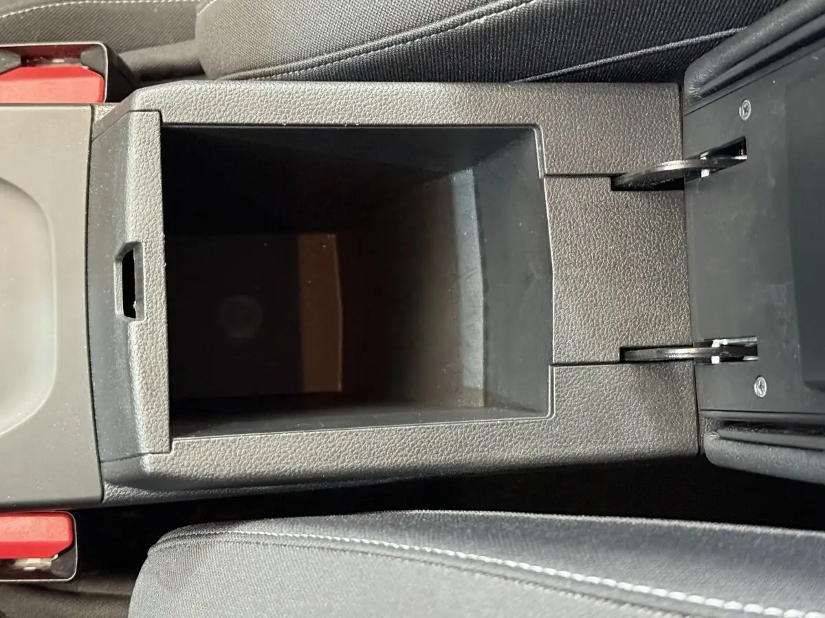 Vue en plongée sur le rangement central noir de l’habitacle du Renault Arkana Business E-TECH 145 bleu de 2022.