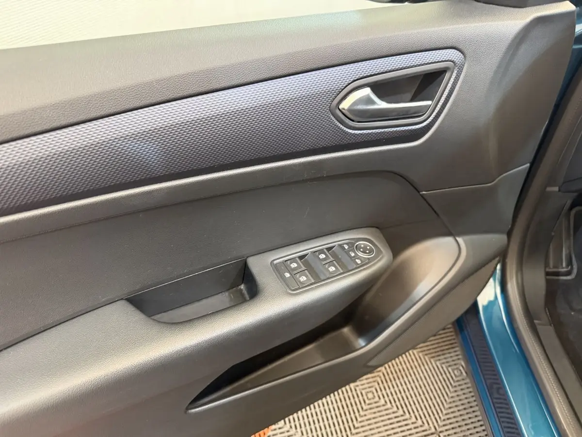 Vue rapprochée de la porte avant gauche bleu métallisé du Renault Arkana avec commandes électriques des vitres et poignée intérieure.