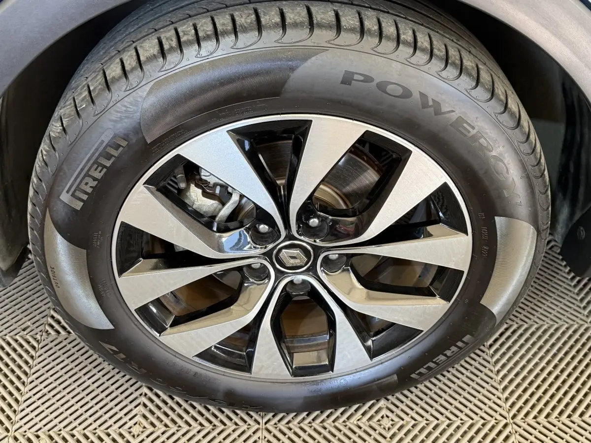 Gros plan sur la jante alu bicolore et le pneu Pirelli d'une Renault Arkana Business E-TECH bleu, vue côté roue avant.