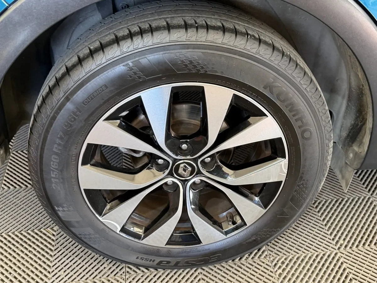 Gros plan sur la roue avant droite d’un Renault Arkana bleu, avec jante alliage bicolore et pneu Kumho.