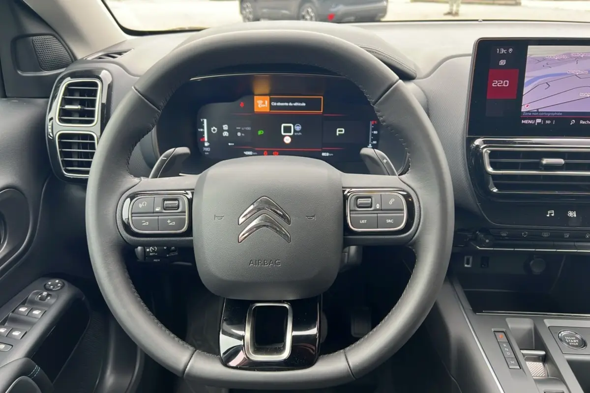 Vue intérieure centrée sur le volant cuir multifonctions du Citroën C5 Aircross Hybrid noir avec tableau de bord digital.