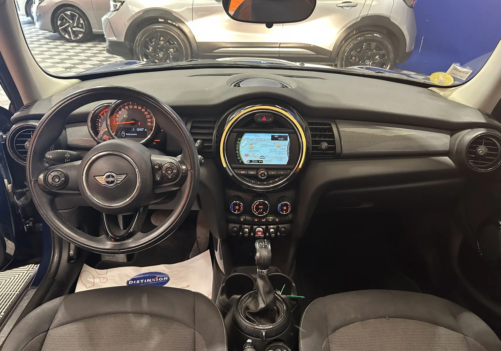 Vue intérieure avant de la MINI 5P Cooper D bleu, avec tableau de bord et écran GPS central lumineux.