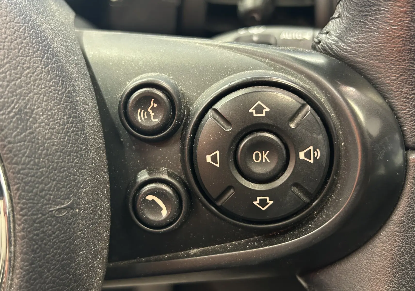 Gros plan sur les commandes vocales et multimédia noires sur le volant d'une MINI 5 portes bleu, version Cooper D 2015.