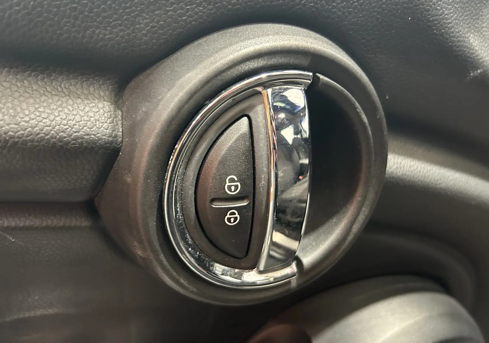 Gros plan sur la poignée de porte intérieure chromée avec boutons de verrouillage d’une MINI 5 portes noire.