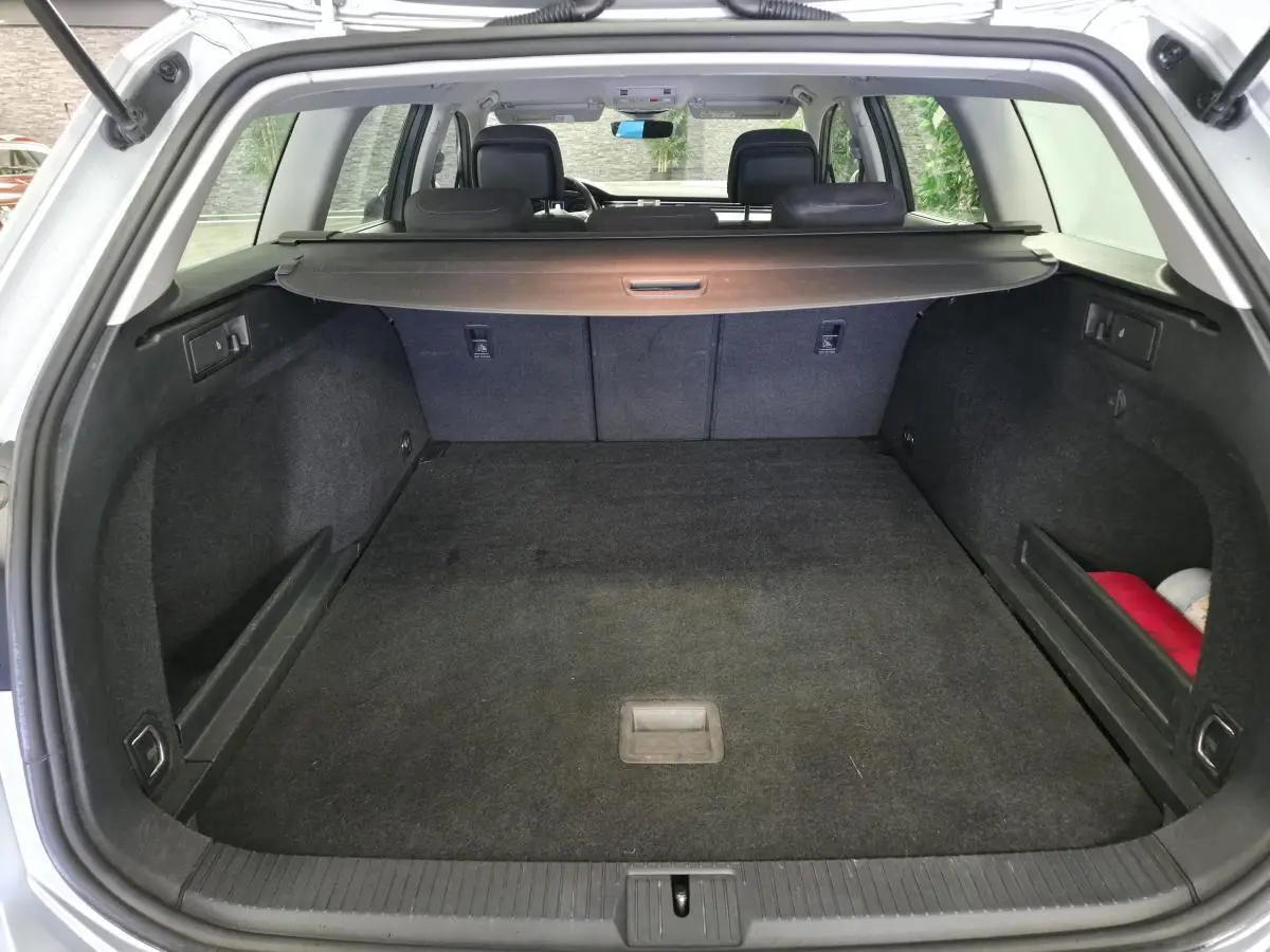 Coffre ouvert d’une Volkswagen Passat SW gris, vue arrière montrant l’espace de chargement et la plage arrière rétractable.