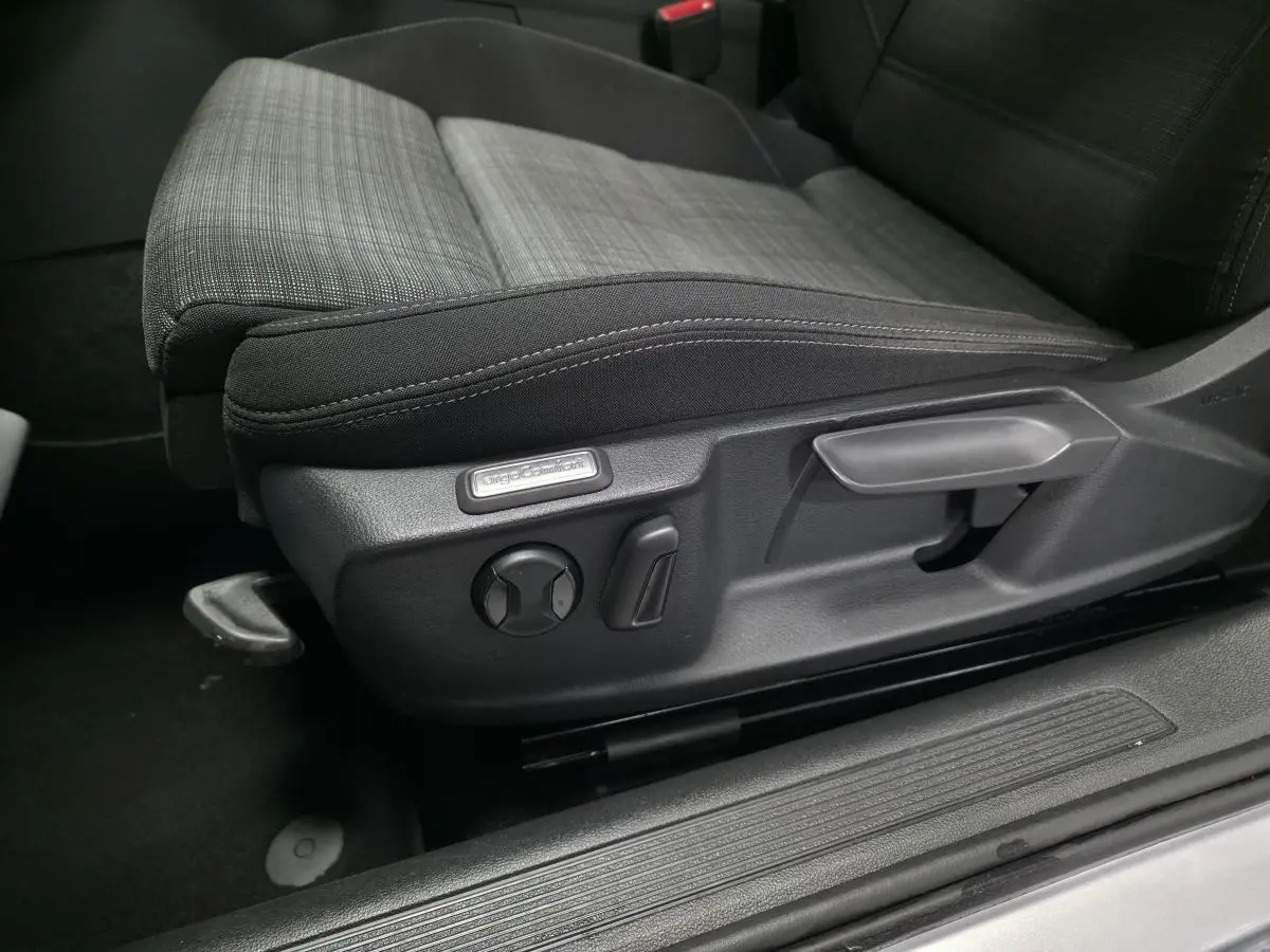 Gros plan sur le siège conducteur tissu gris et noir avec réglages manuels et étiquette "ErgoComfort" dans une Volkswagen Passat SW 2021.