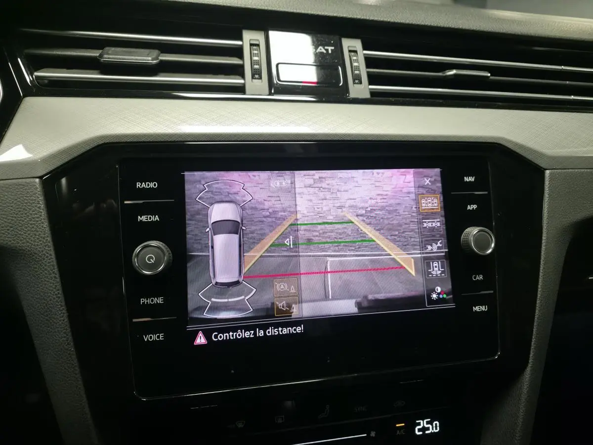 Écran tactile central affichant la caméra de recul et l'aide au stationnement de la Volkswagen Passat SW gris, vue intérieure.