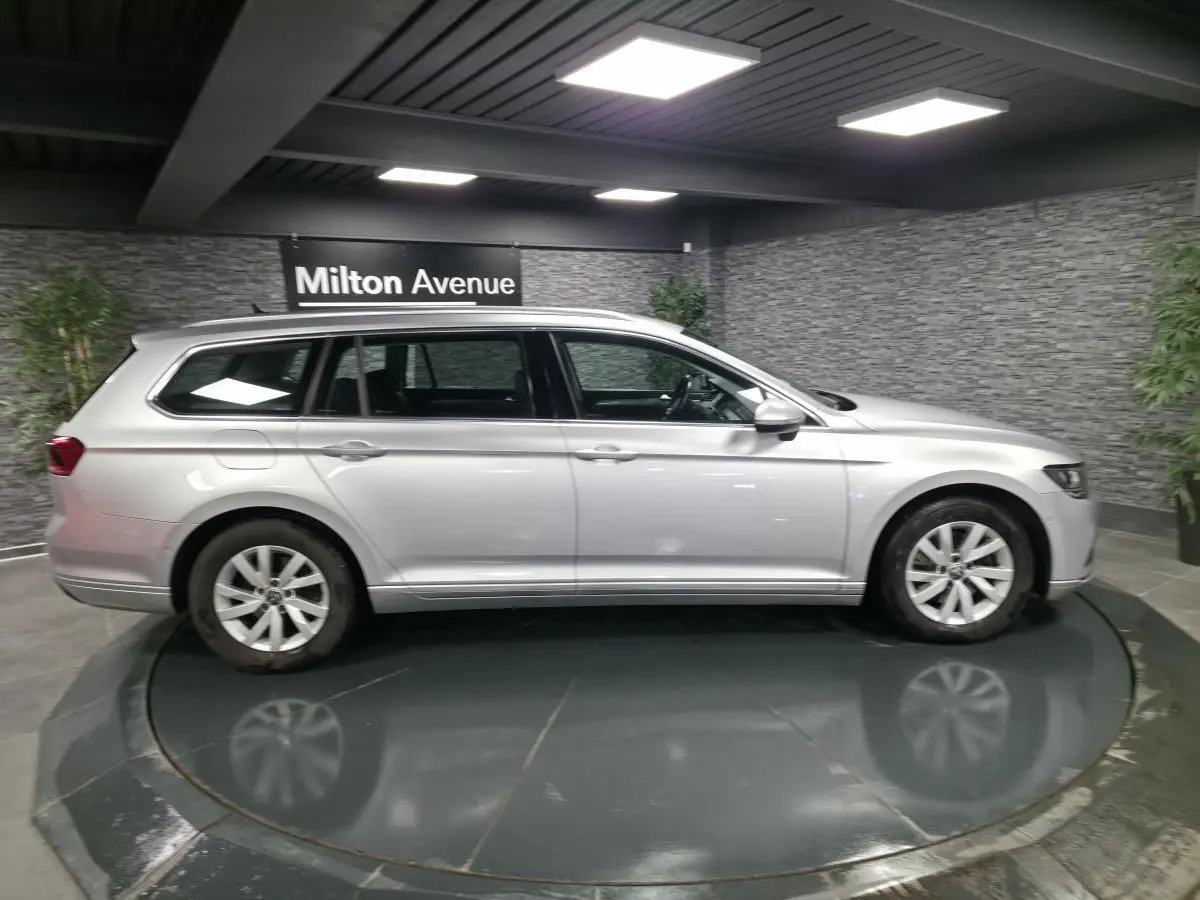 Volkswagen Passat SW gris métallisé vue de profil côté gauche dans un showroom intérieur sobre.