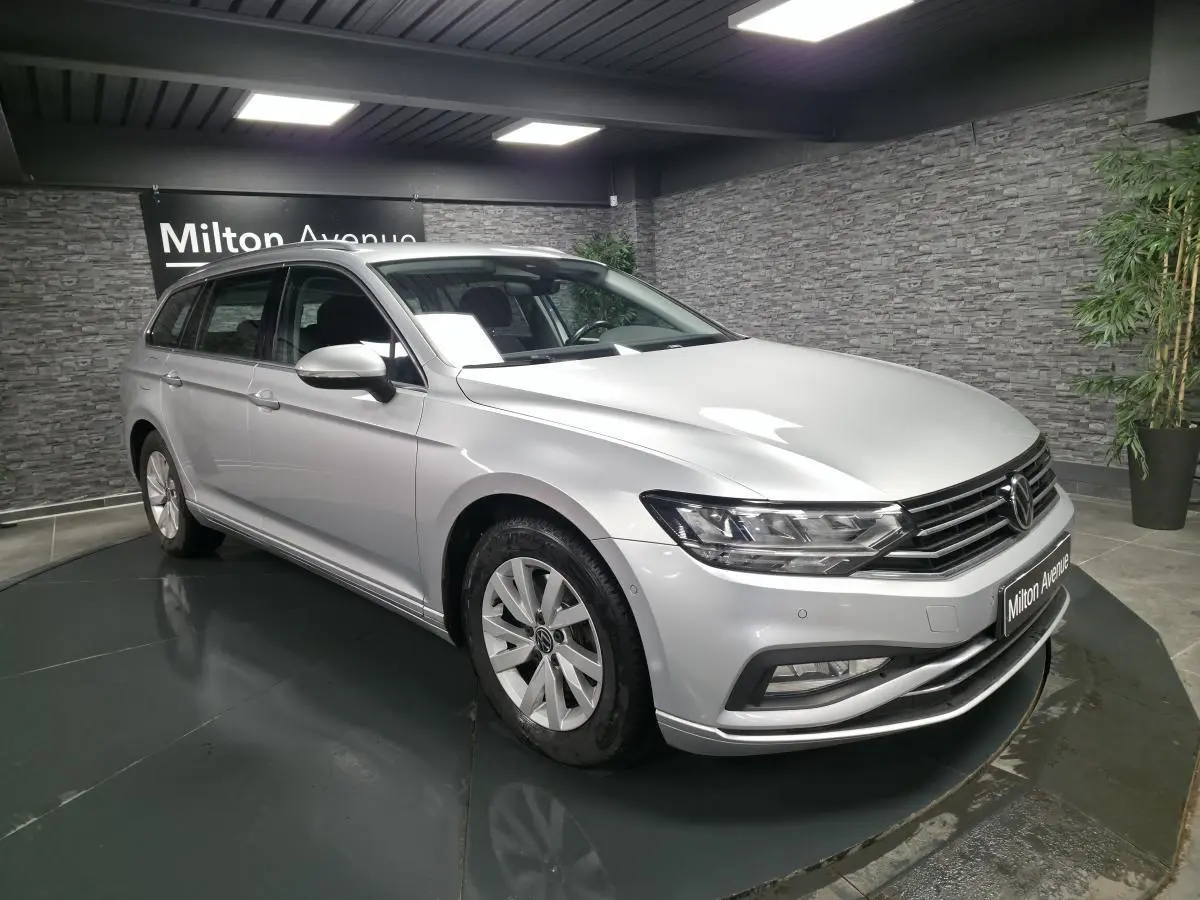 Volkswagen Passat SW gris métallisé vue 3/4 avant droit en intérieur avec jantes alliage et calandre chromée.