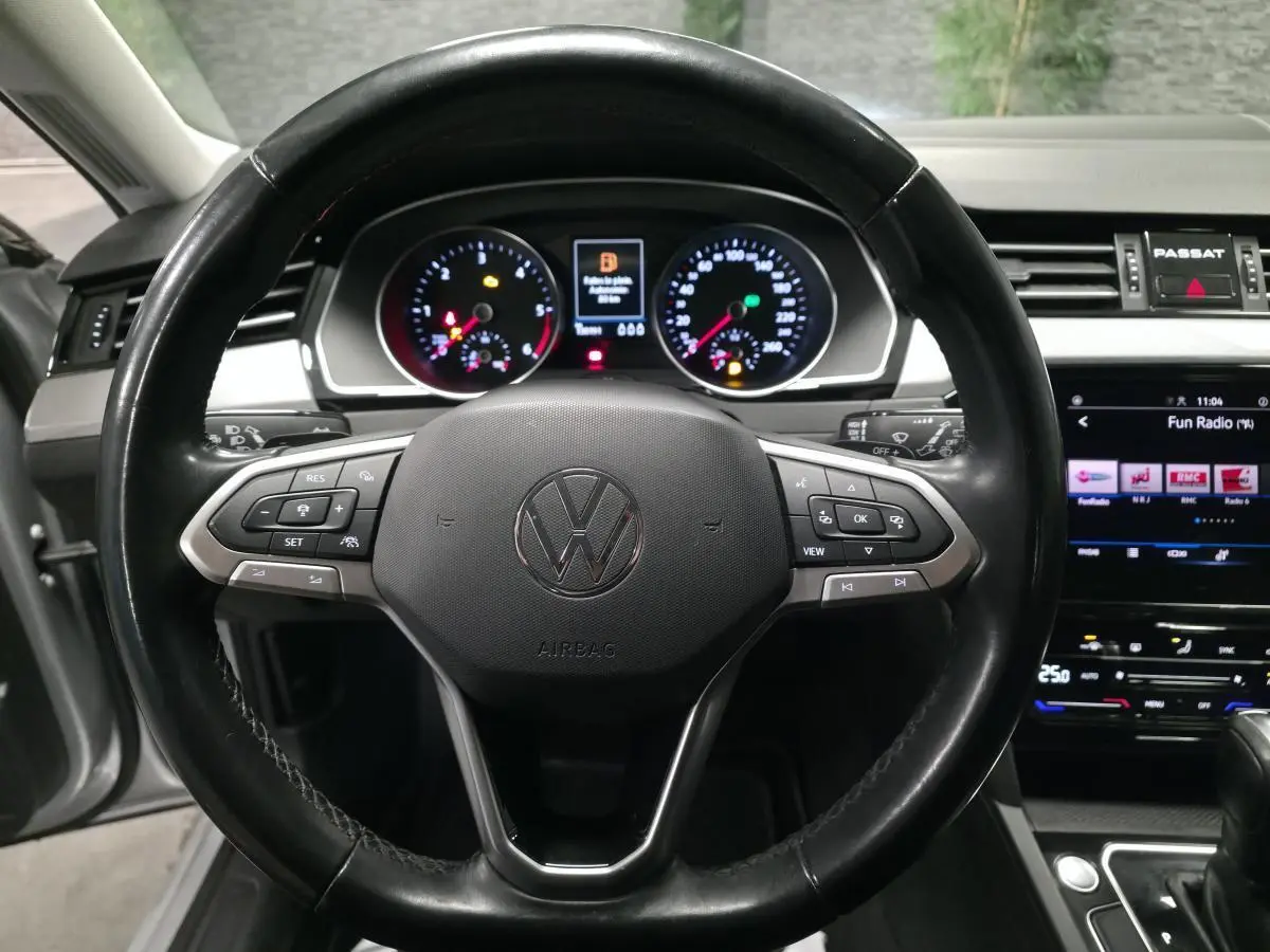 Vue intérieure centrée sur le volant cuir multifonction de la Volkswagen Passat SW 2021 avec tableau de bord et écran tactile.