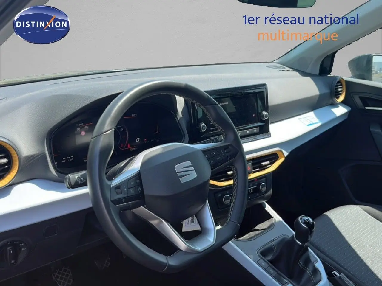 Vue intérieure côté conducteur du tableau de bord et volant d'une SEAT Arona gris magnetic avec toit blanc, boîte manuelle.