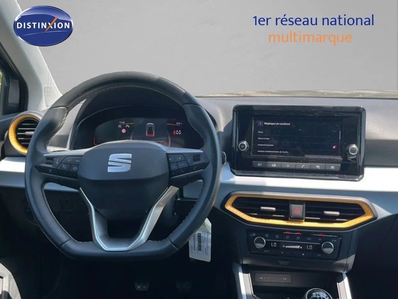Vue frontale de l'intérieur du SEAT Arona gris, volant multifonctions et écran tactile avec cadre noir et garniture dorée.