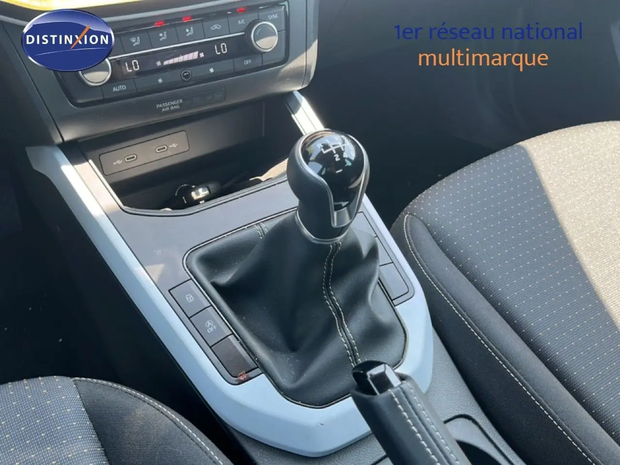 Gros plan sur la console centrale d’une SEAT Arona gris magnetic, avec levier de vitesse manuel et sièges tissu gris.