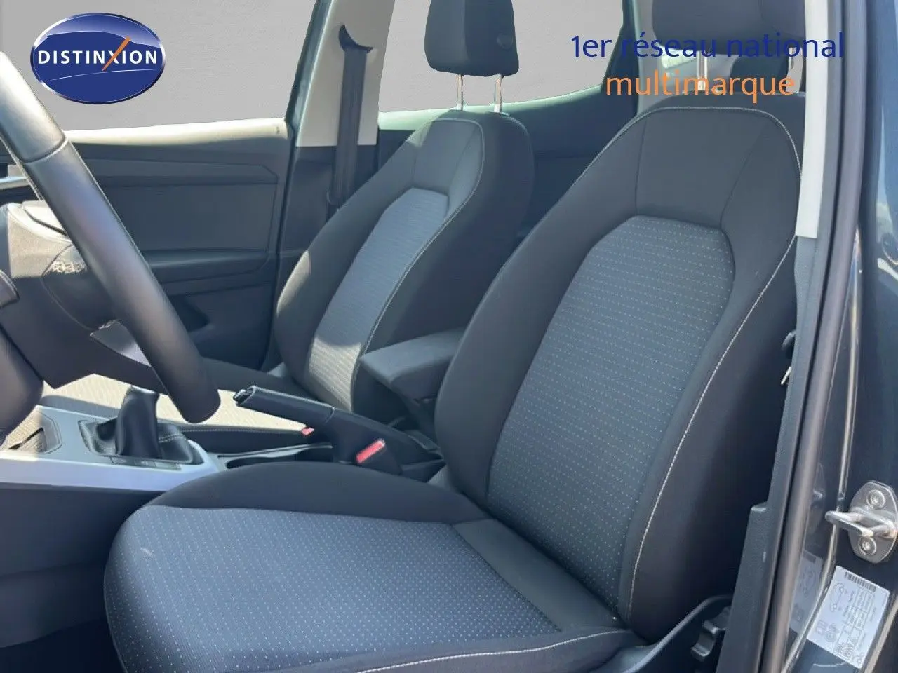 Vue intérieure côté conducteur du SEAT Arona gris magnetic avec sièges tissu gris et noir, volant multifonction et boîte manuelle.