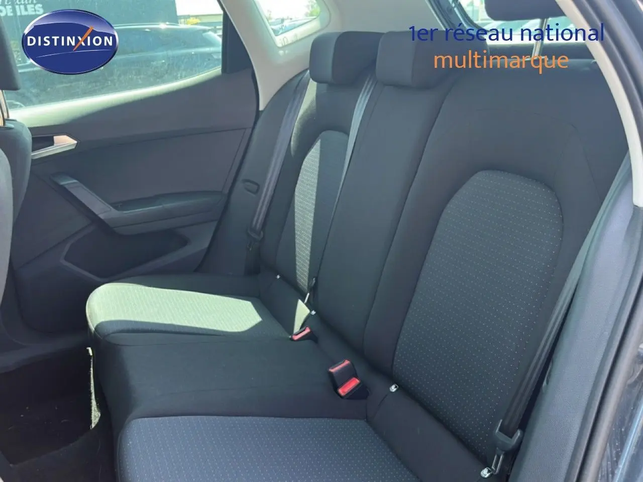 Vue latérale gauche de l’intérieur arrière du SEAT Arona 2026, sièges tissu gris foncé avec ceinture de sécurité.