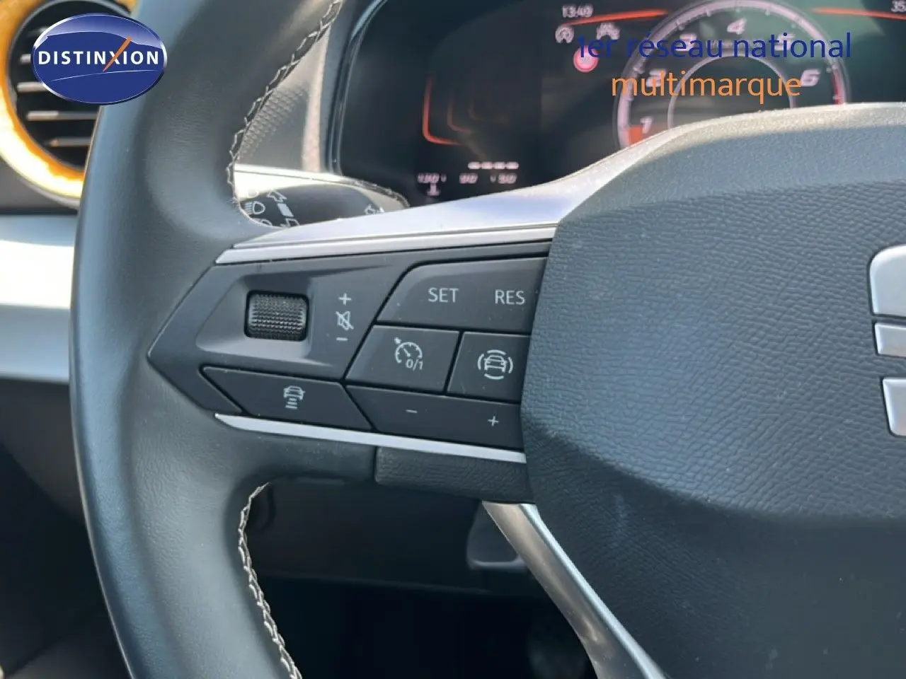 Gros plan sur le volant de la SEAT Arona 2026, montrant les commandes multifonctions à gauche avec tableau de bord digital en arrière-plan.