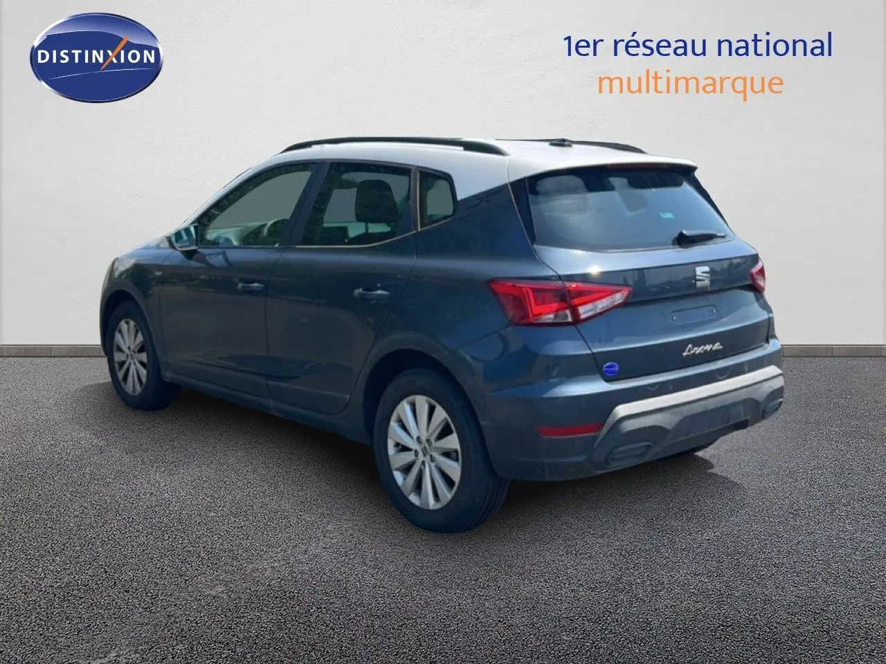 Vue 3/4 arrière gauche d'un SEAT Arona gris magnetic avec toit blanc, mettant en valeur ses feux arrière et jantes.
