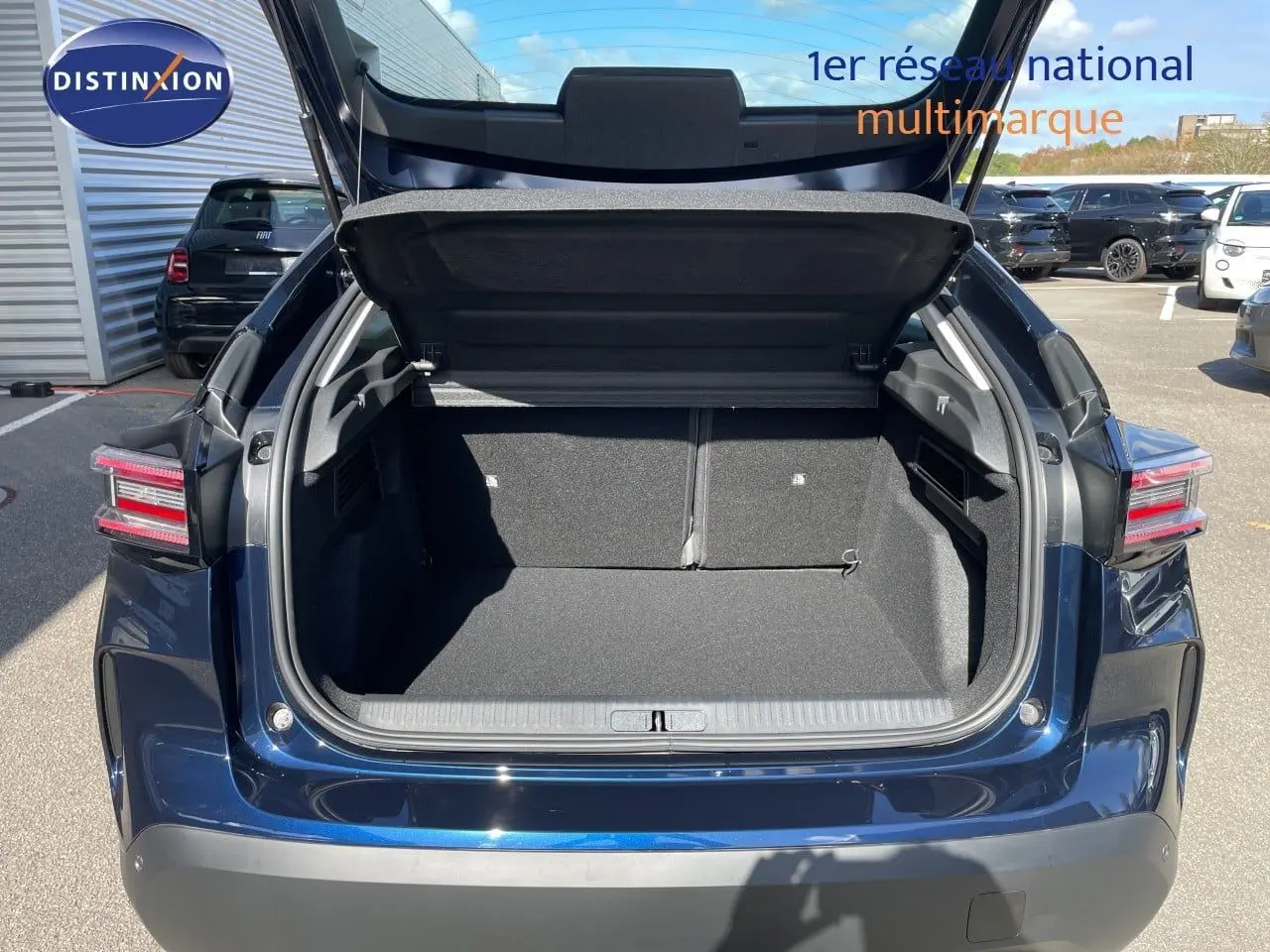 Coffre ouvert vu de l'arrière d'une Citroën C4 Hybrid 145ch bleu eclipse métal, avec feux arrière LED distinctifs.