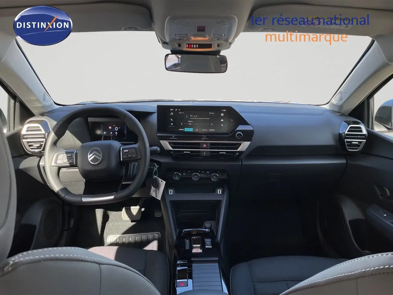 Vue intérieure avant du tableau de bord et volant noir d'une Citroën C4 Hybrid 145ch BVA Plus, finition moderne et épurée.