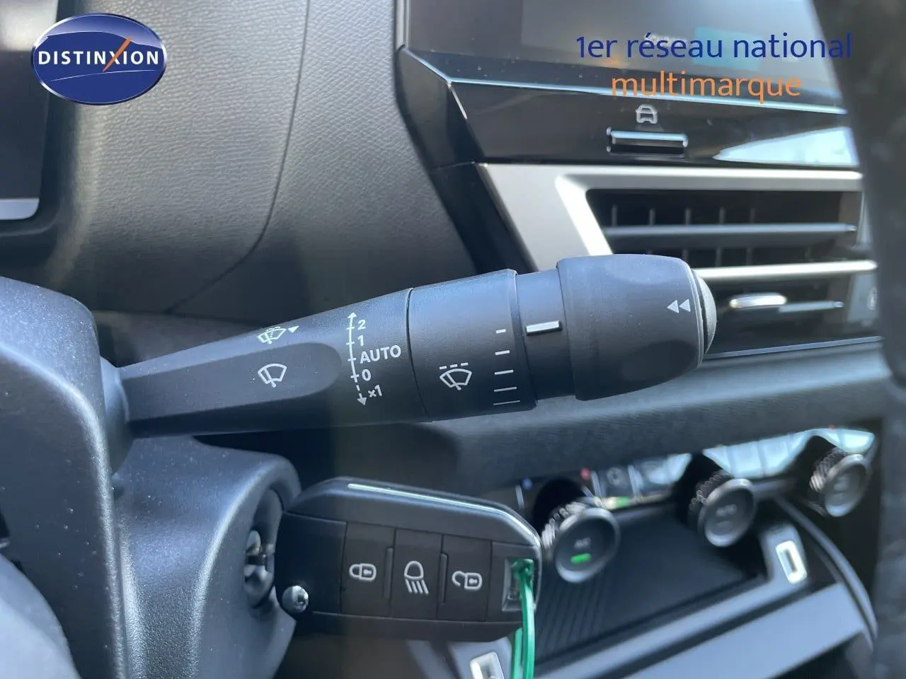 Gros plan sur la commande d’essuie-glace et la clé de contact dans l’habitacle d’une Citroën C4 hybride bleu Eclipse métal.