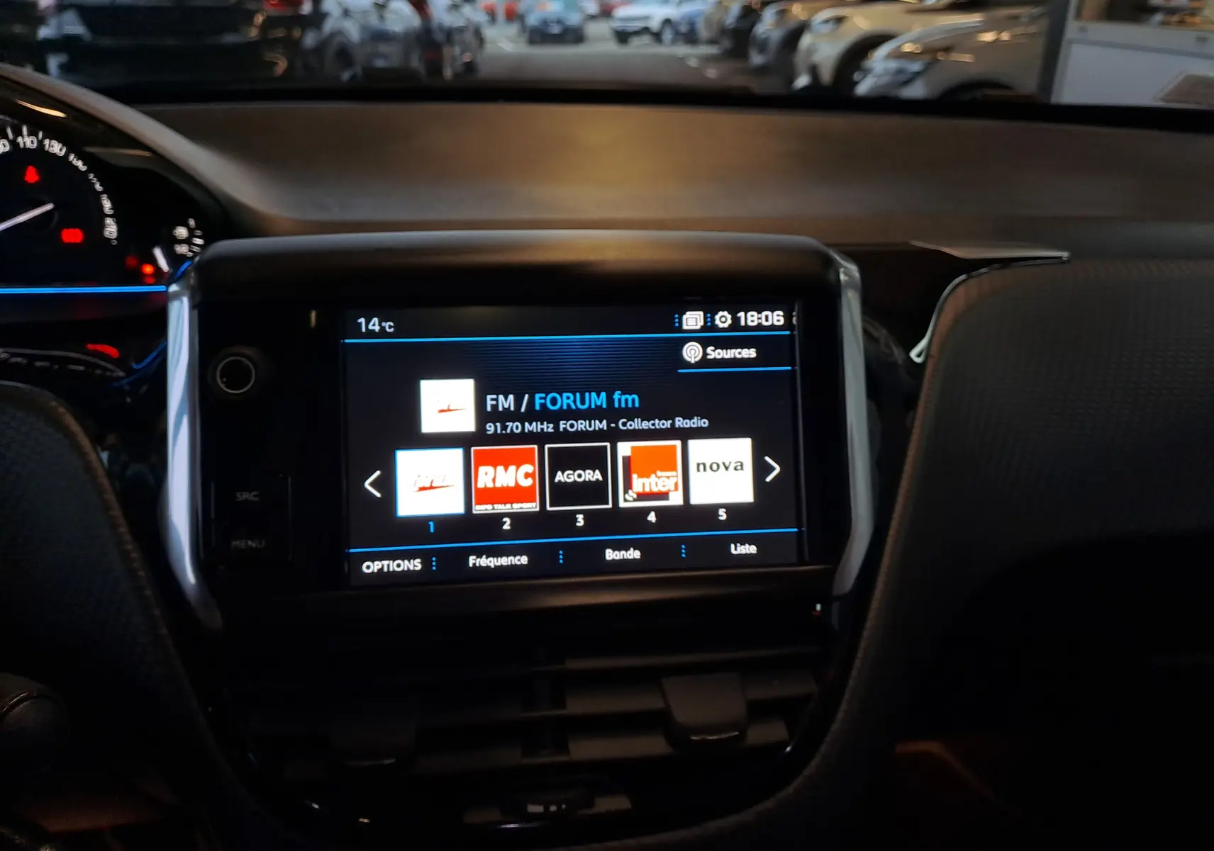 Écran tactile central du tableau de bord du Peugeot 2008 gris, affichant les stations radio FM en soirée.