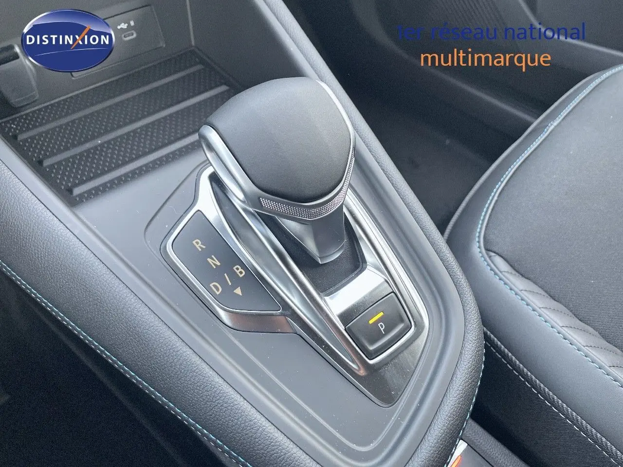 Le levier de vitesses automatique noir avec surpiqûres bleues de la Renault Symbioz 2024 en gros plan intérieur.