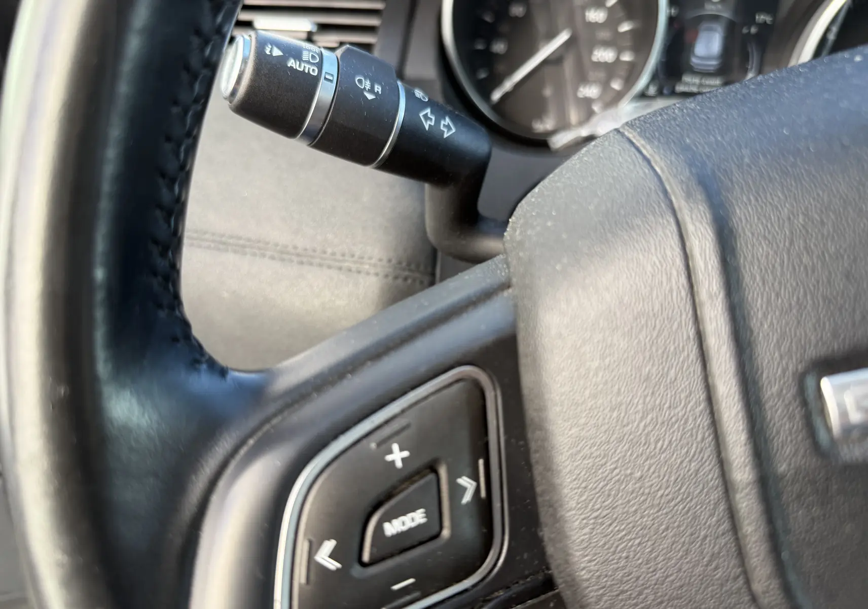 Gros plan sur le volant noir et la commande de clignotant du Range Rover Evoque gris, version 2017, côté gauche.