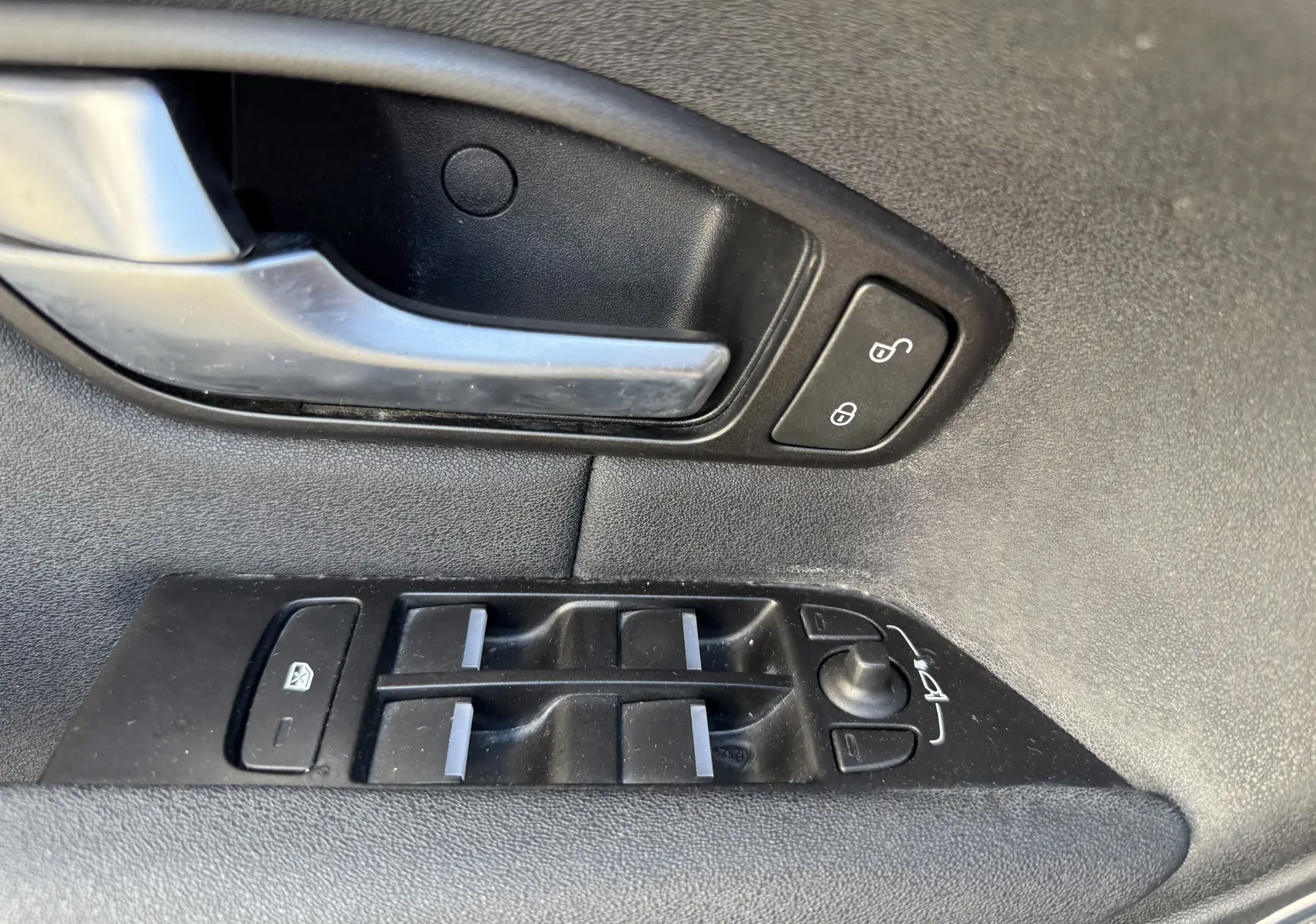 Gros plan sur la commande des vitres et la poignée intérieure côté gauche du Range Rover Evoque gris 2017.