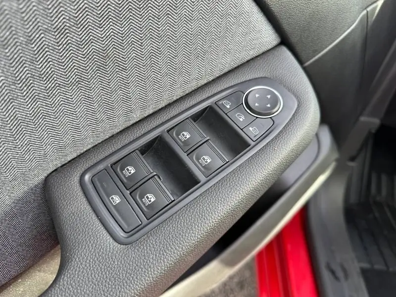 Gros plan sur les commandes de vitres électriques côté conducteur d’une Renault Clio Rouge Flamme 2025, intérieur tissu gris.
