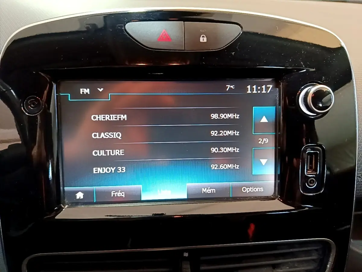 Écran tactile central de la Renault Clio Zen Energy 2016 affichant les stations radio FM, entouré de boutons noirs brillants.