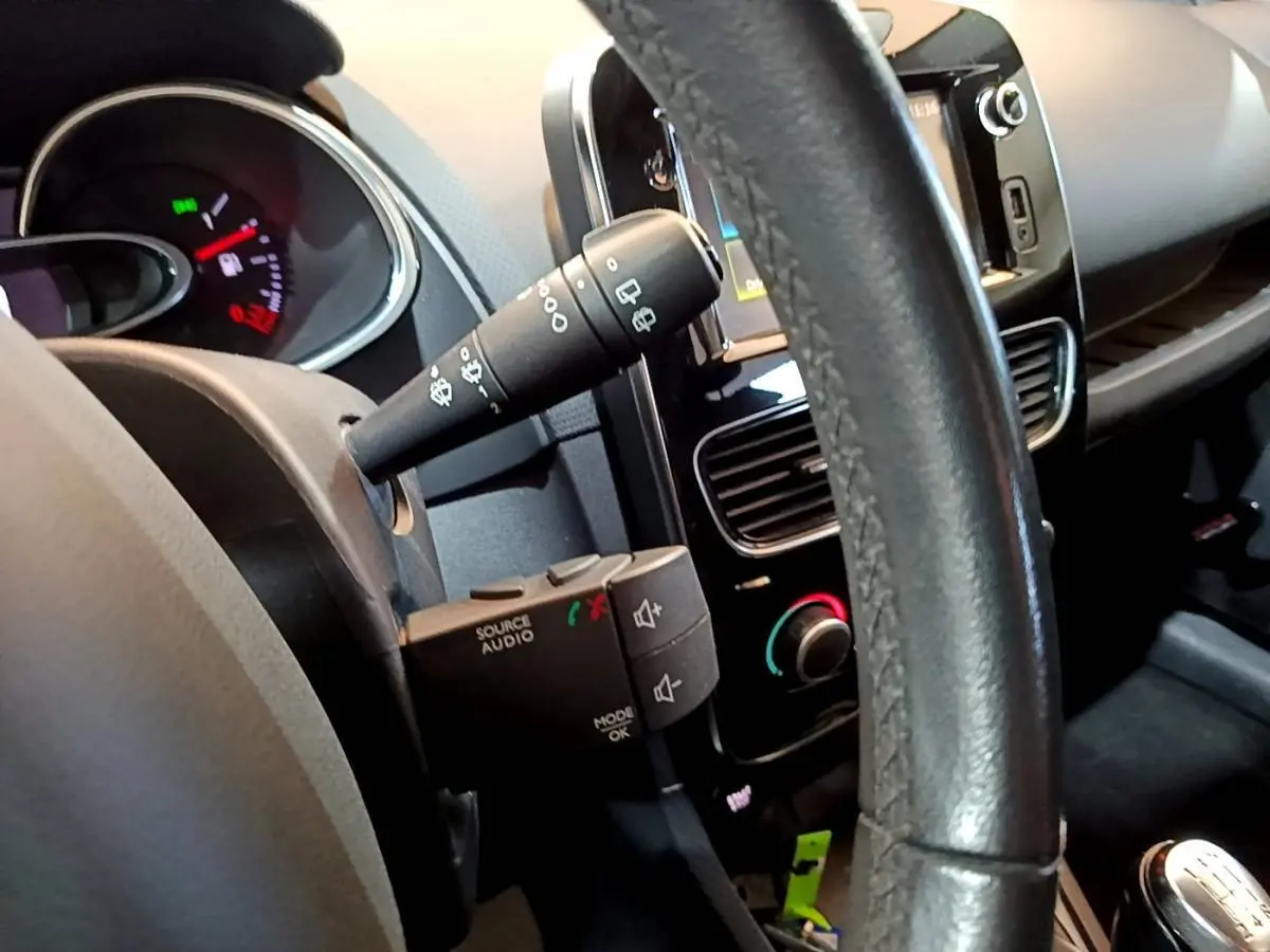 Vue rapprochée de l’intérieur de la Renault Clio blanche, volant cuir multifonctions et tableau de bord avec écran tactile.