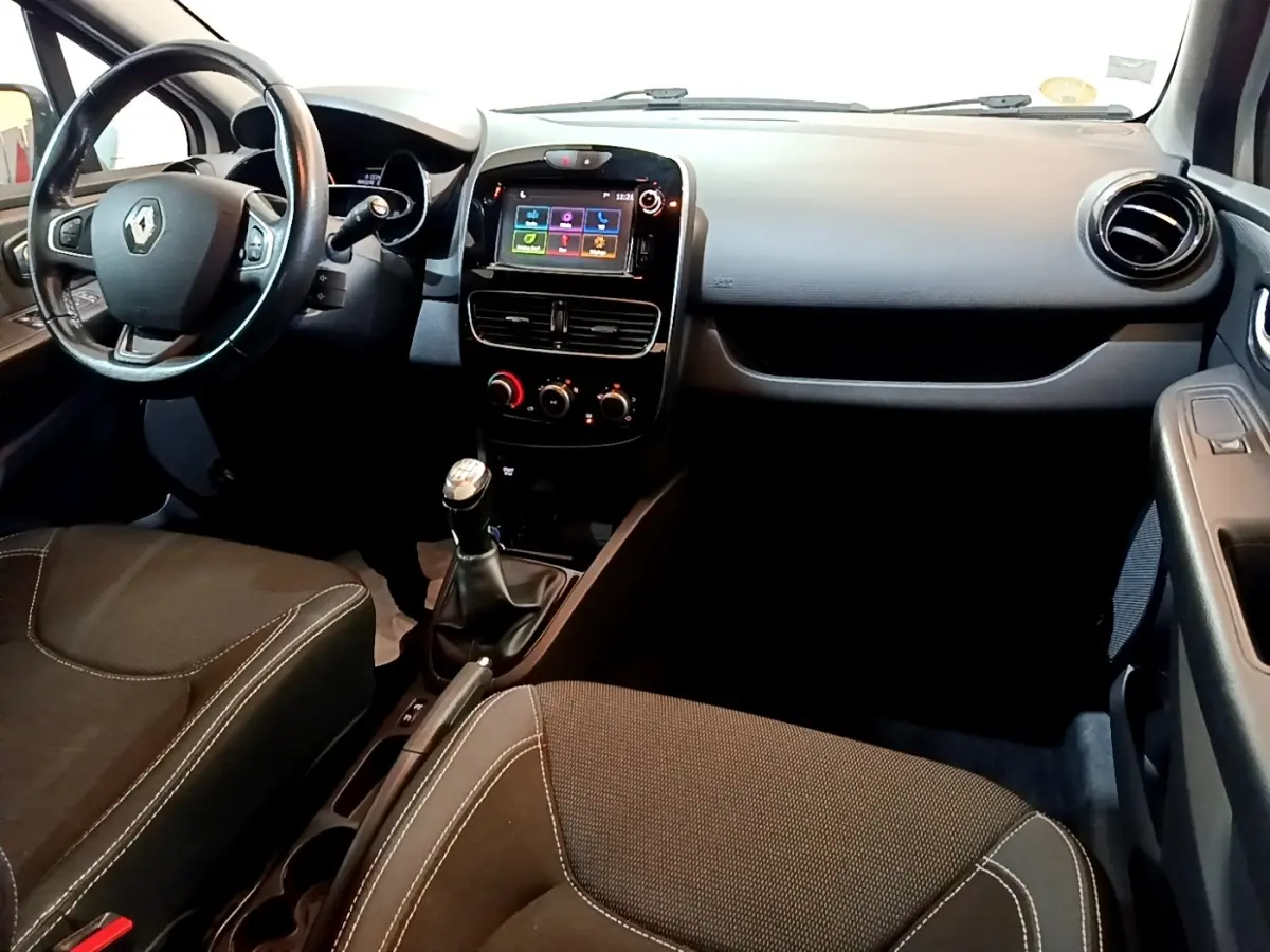 Vue intérieure avant droite de la Renault Clio blanche 2016, volant cuir multifonctions et écran tactile central.