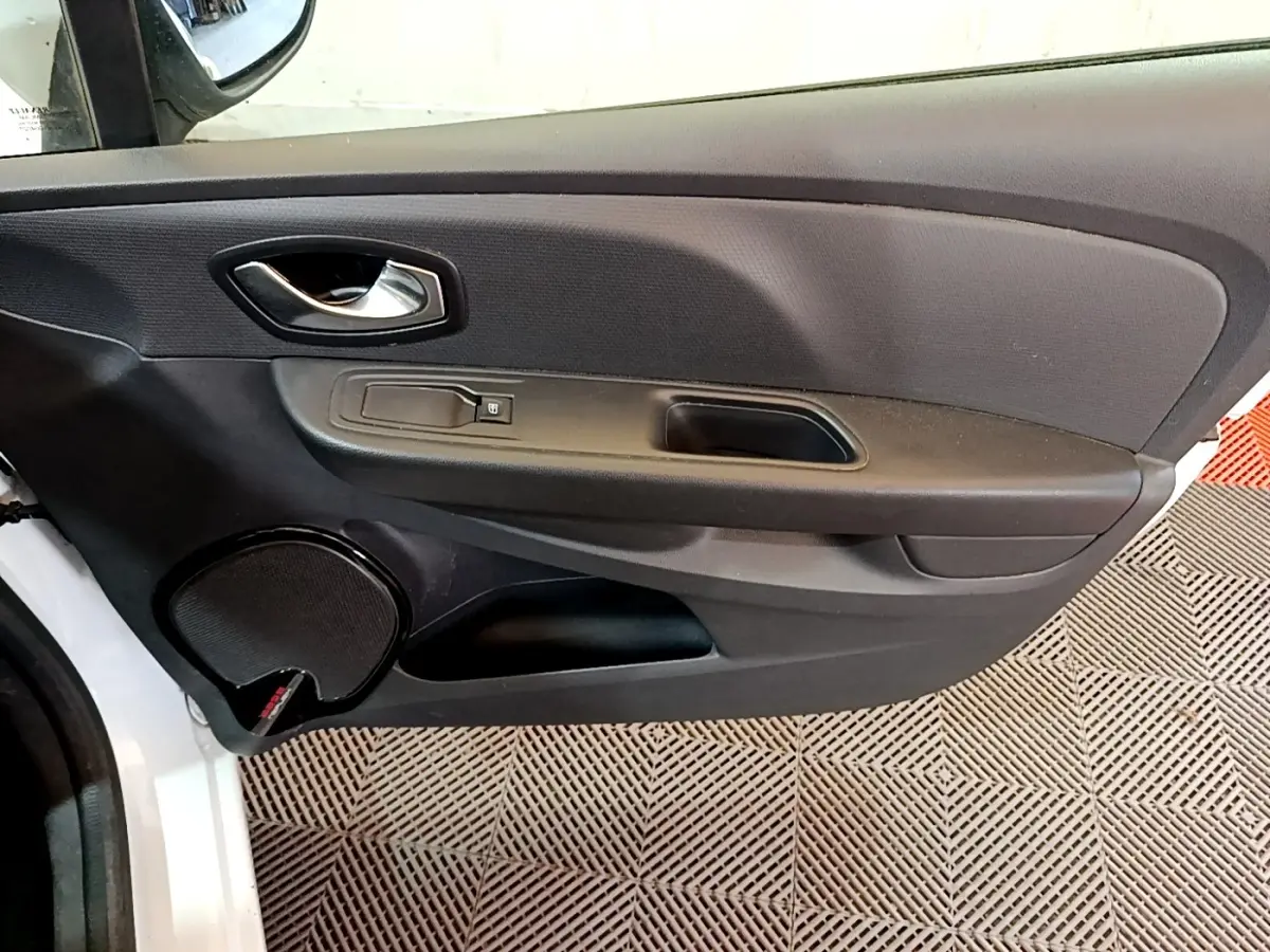 Vue rapprochée de la porte avant gauche noire d'une Renault Clio Zen Energy dCi 75 blanche, avec poignée et haut-parleur intégrés.