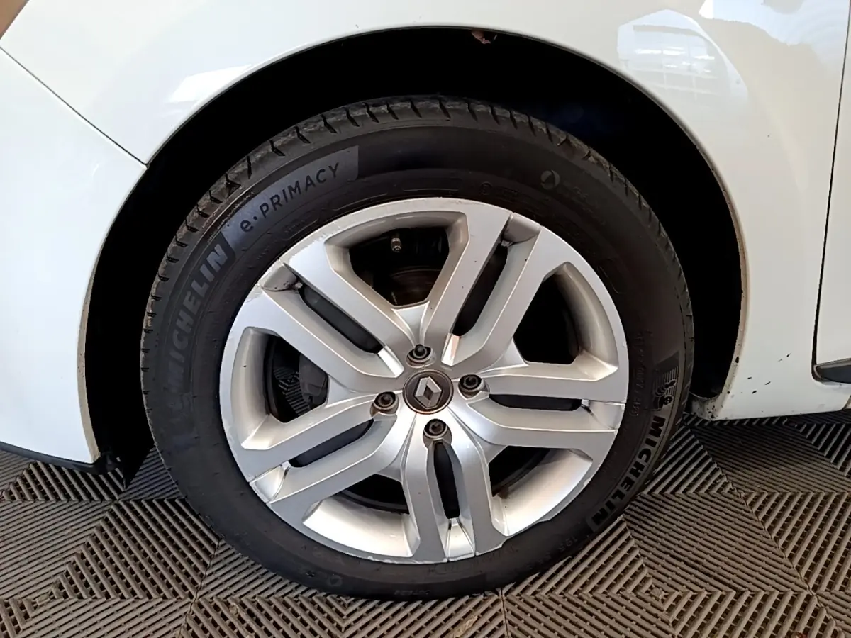 Gros plan sur la roue avant gauche d'une Renault Clio blanche, jante alliage à cinq doubles branches.