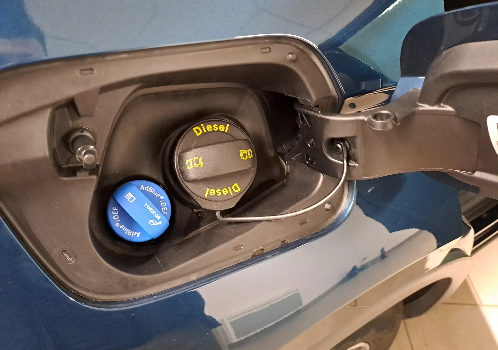 Gros plan sur la trappe à carburant d’un Volkswagen Tiguan 2023 bleu Nightshade avec bouchons Diesel et AdBlue visibles.