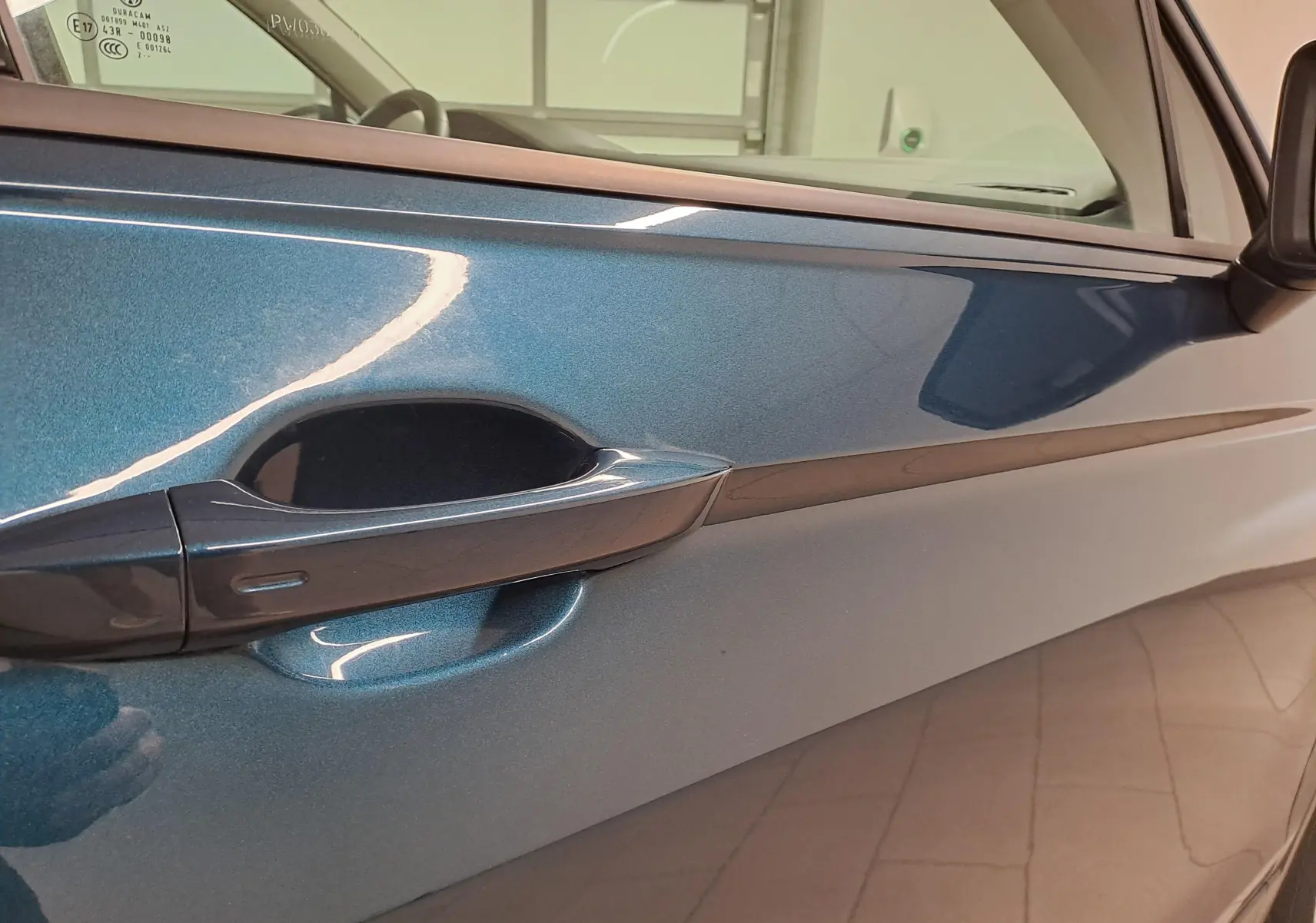 Gros plan sur la poignée de porte côté gauche d’un Volkswagen Tiguan 2023 en bleu Nightshade métallisé.