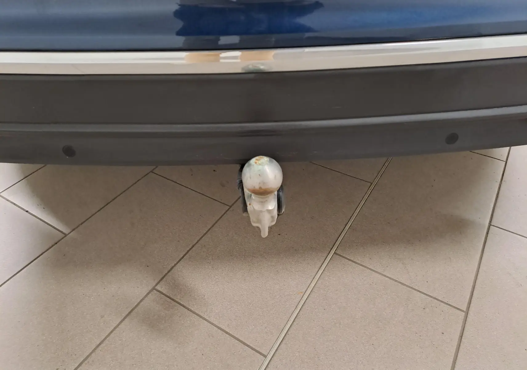Gros plan sur le crochet d'attelage escamotable sous le pare-chocs arrière bleu Nightshade du Volkswagen Tiguan 2023.