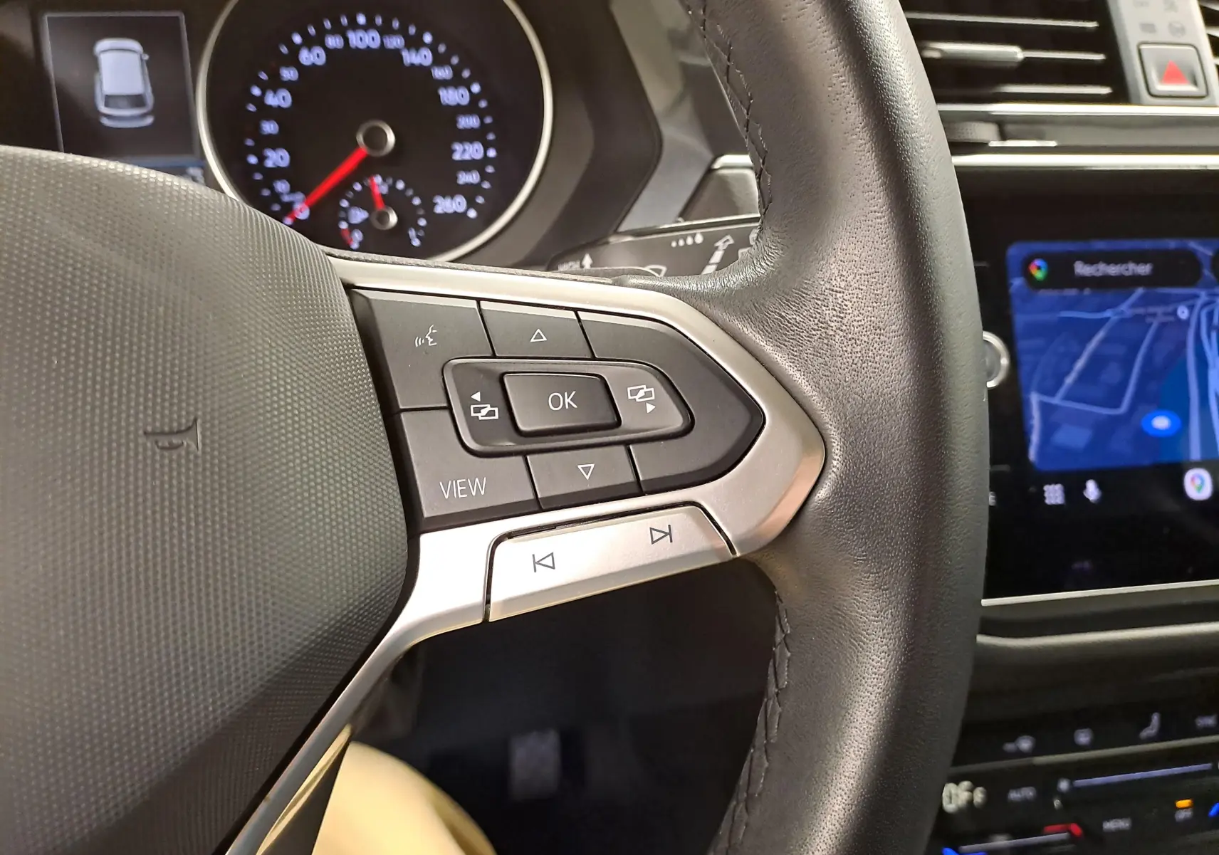 Gros plan sur le volant côté gauche du Volkswagen Tiguan 2023 avec commandes intégrées et tableau de bord numérique.