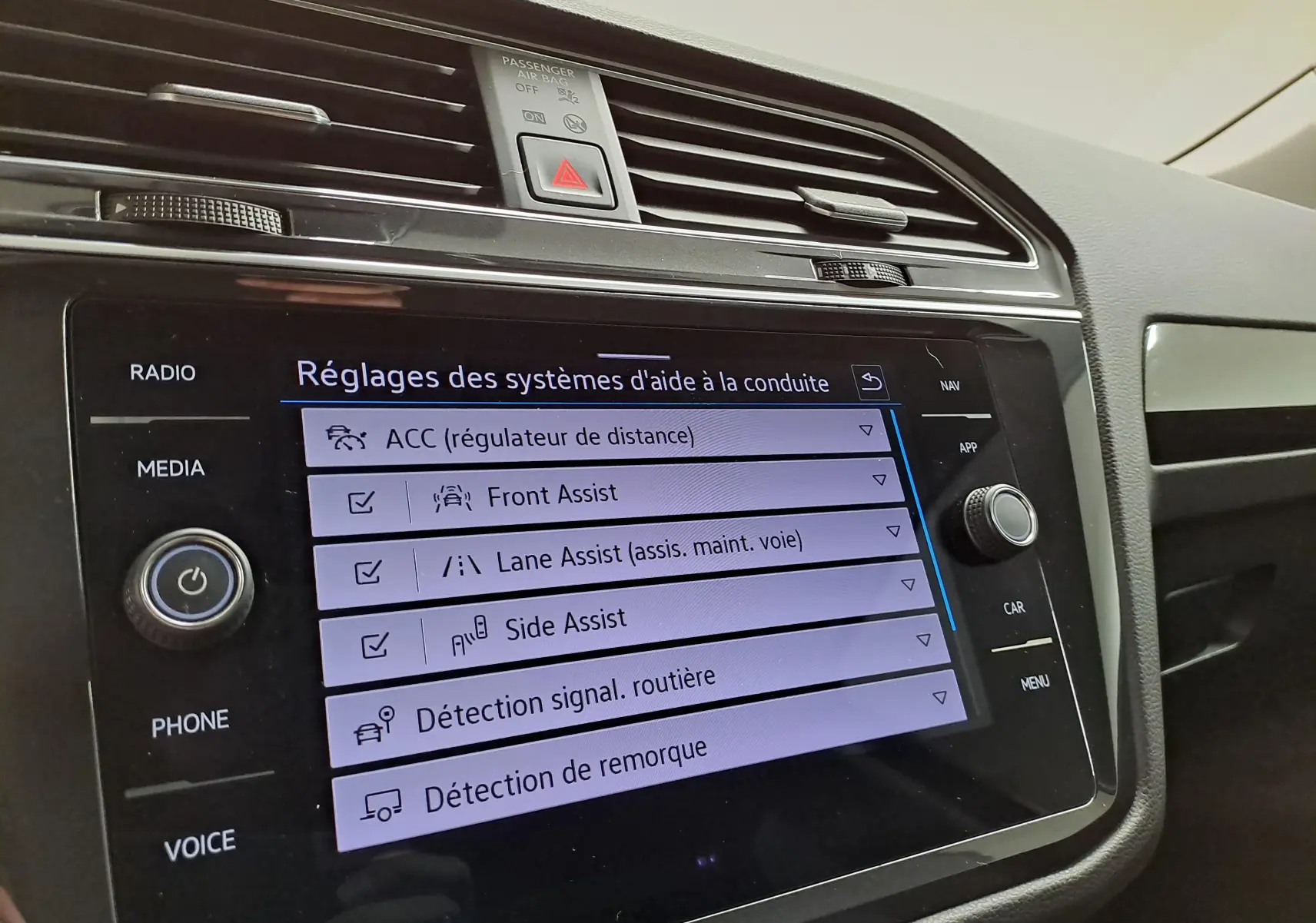 Vue rapprochée de l'écran tactile du tableau de bord du Volkswagen Tiguan 2023 affichant les réglages des aides à la conduite.