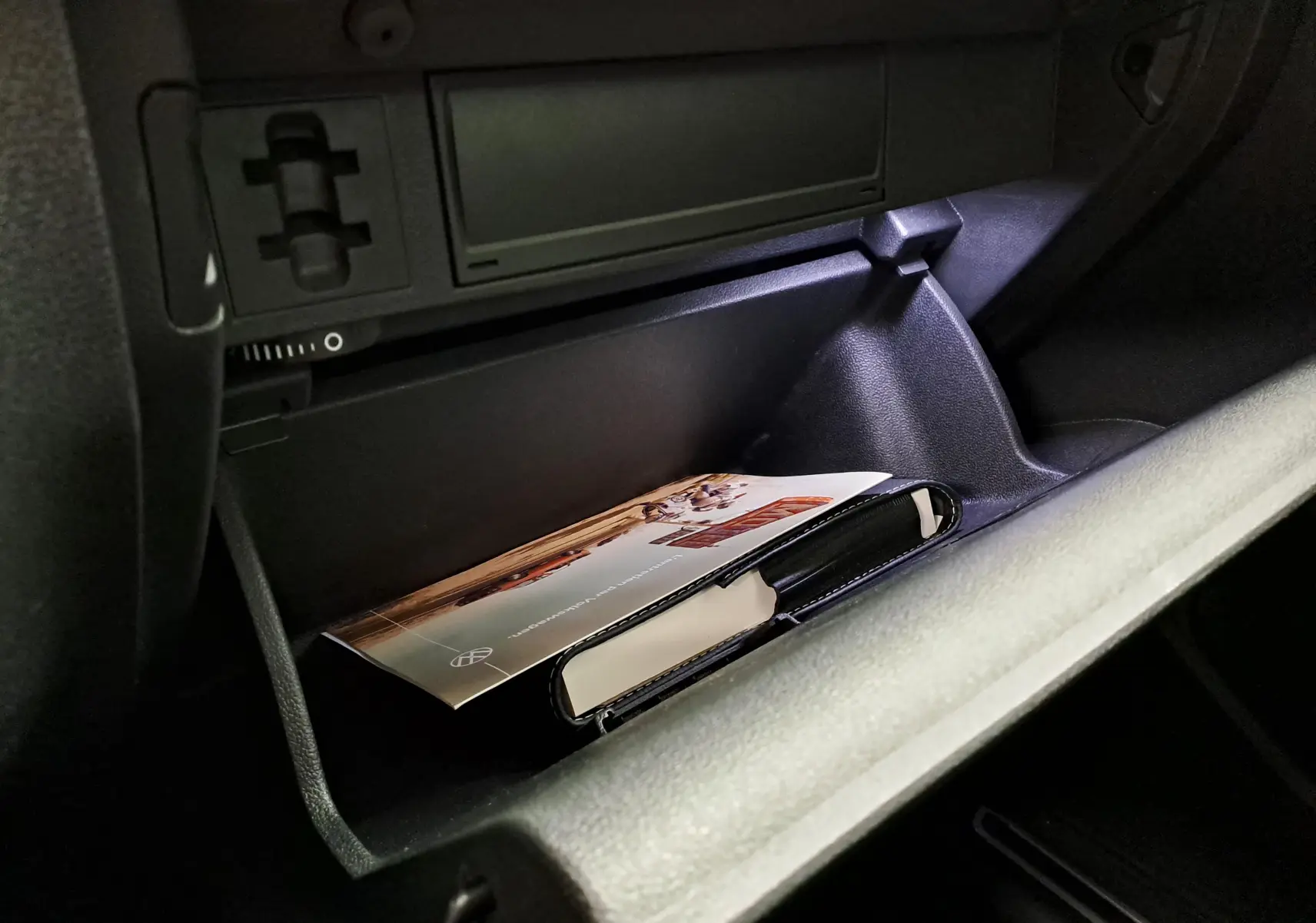 Gant de boîte à gants ouvert dans un Volkswagen Tiguan 2023, montrant un livret et un étui noir à l'intérieur.