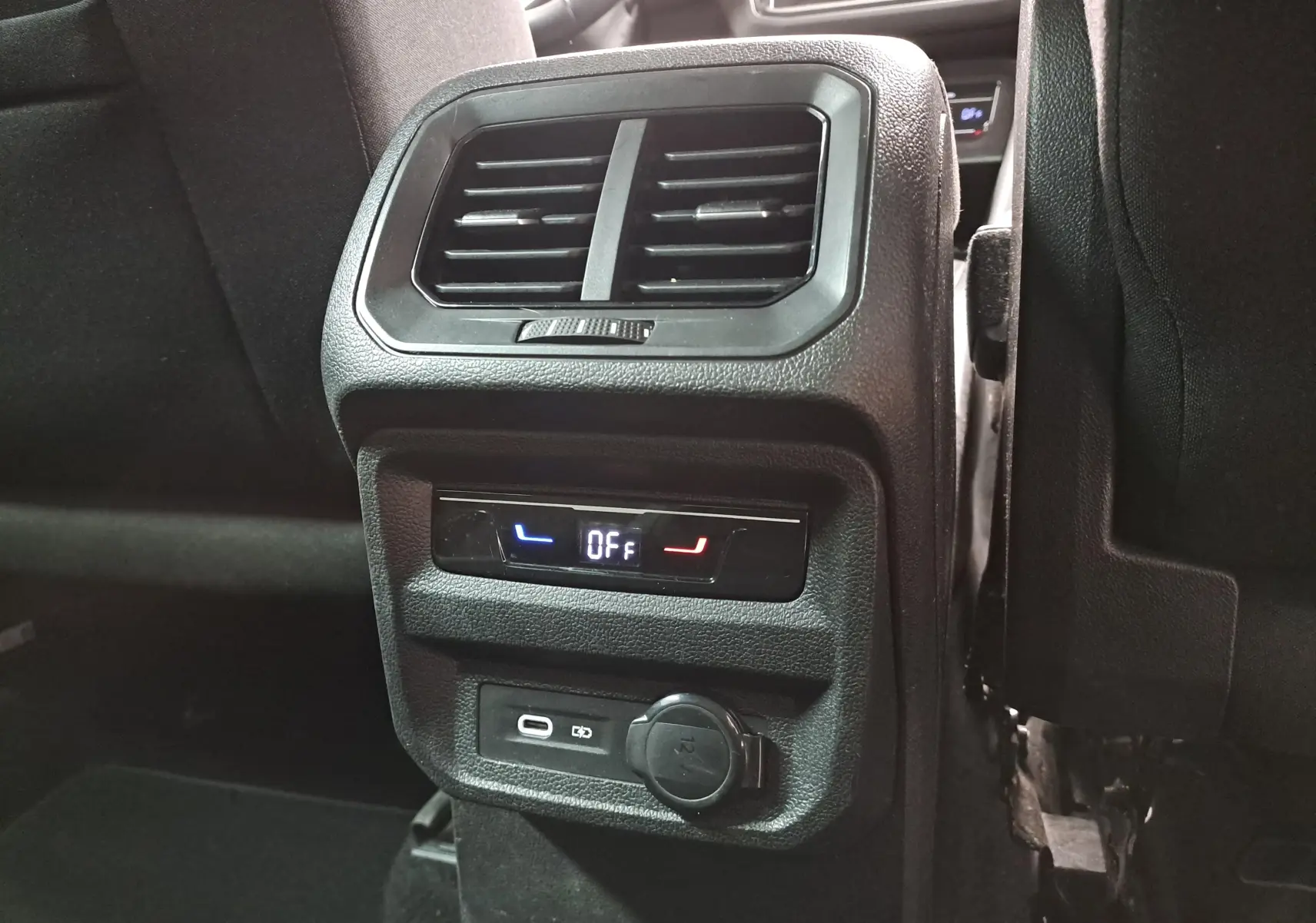 Vue rapprochée de la console arrière noire du Volkswagen Tiguan 2023 avec commandes de climatisation et prises USB.