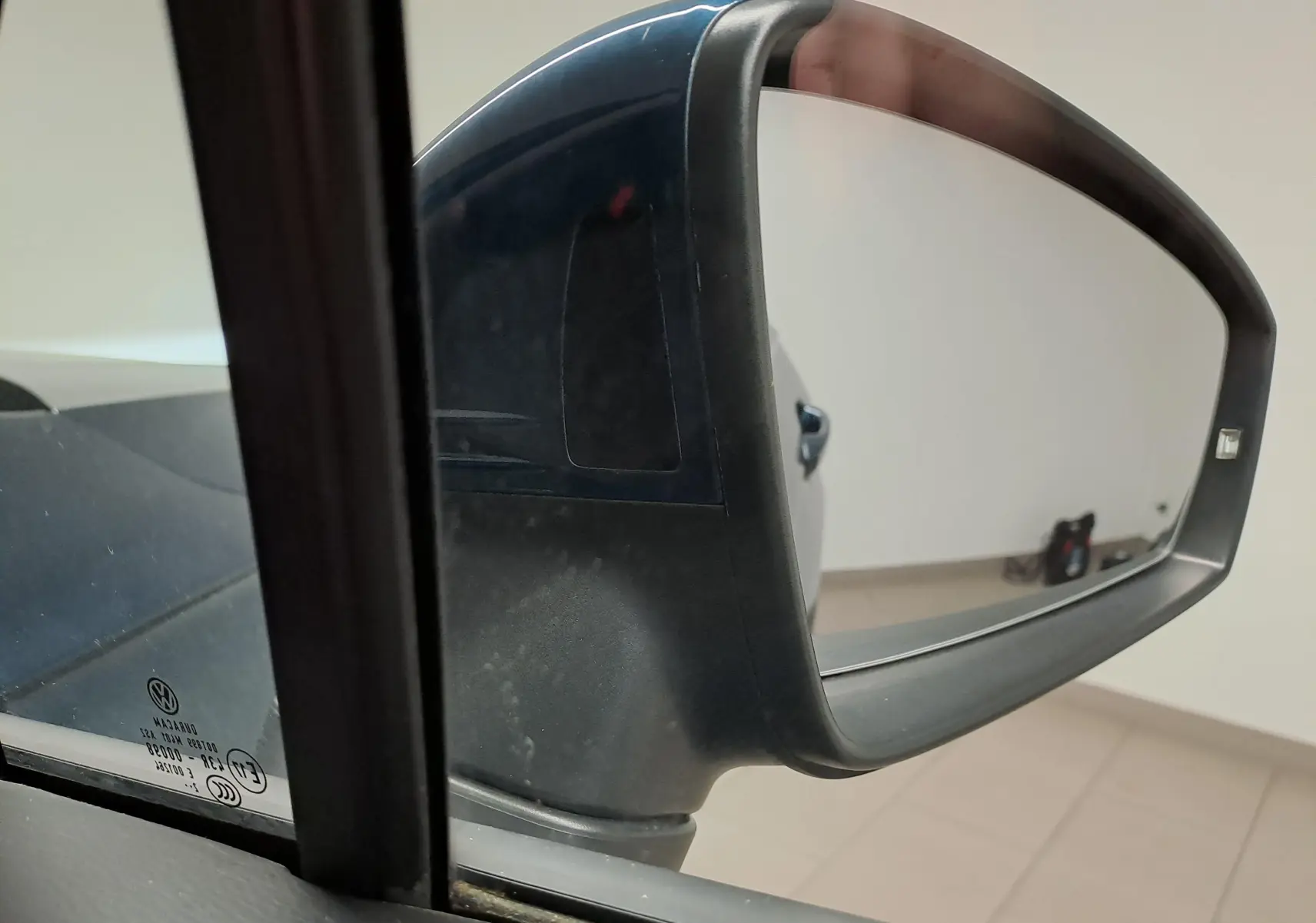 Rétroviseur extérieur côté gauche du Volkswagen Tiguan 2023 Nightshade Blue avec peinture métallisée visible.