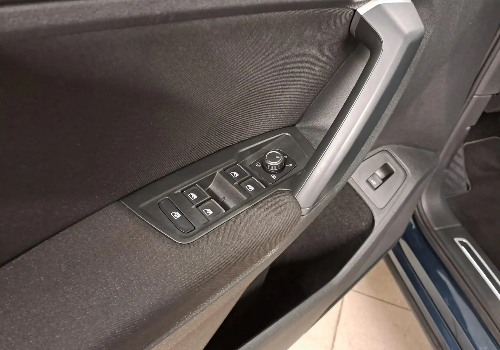 Gros plan sur la commande des vitres et rétroviseurs côté conducteur du Volkswagen Tiguan 2023 en Nightshade Blue.